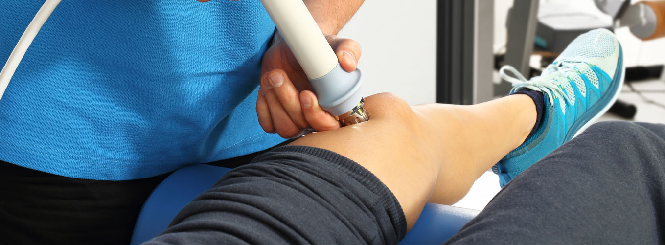 Clinician applying a handheld treatment device to a knee