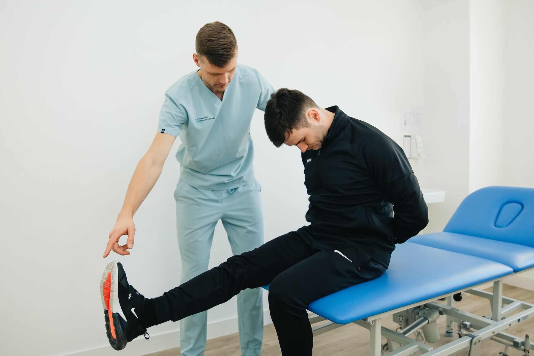 A physical therapist guiding a patient through a leg mobility exercise