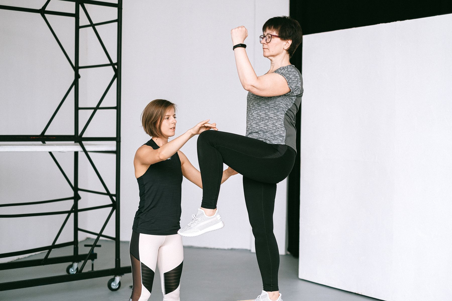 A therapist helping an older adult practice balance and knee mobility